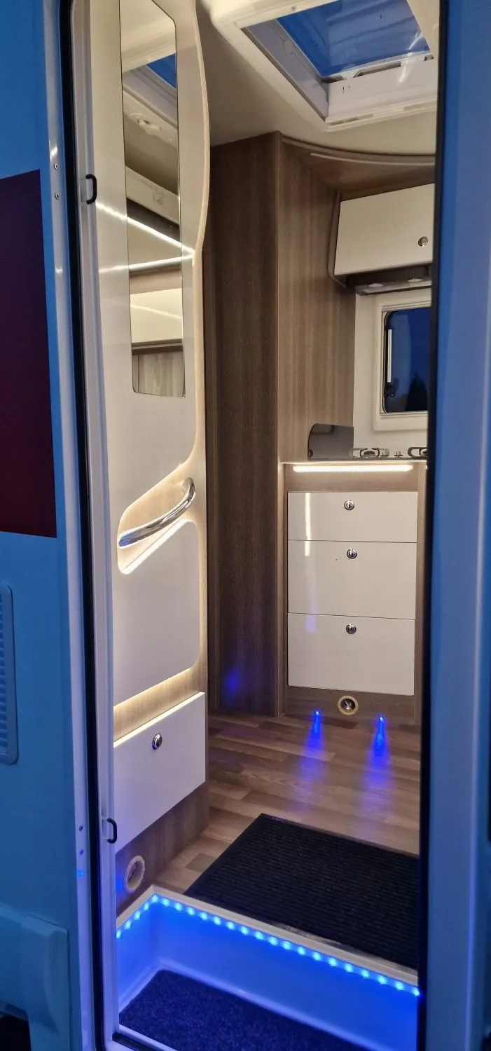 Camper entrance with kitchen cabinets and lighting